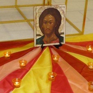 Ein abstraktes Christusbild liegt auf einer bunten Decke mit angezündeten Kerzen