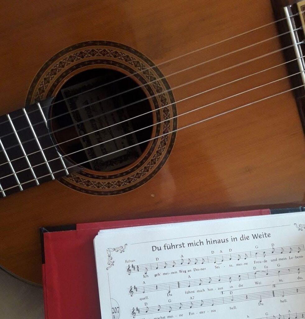Eine Gitarre und ein Notenbuch liegen beieinander