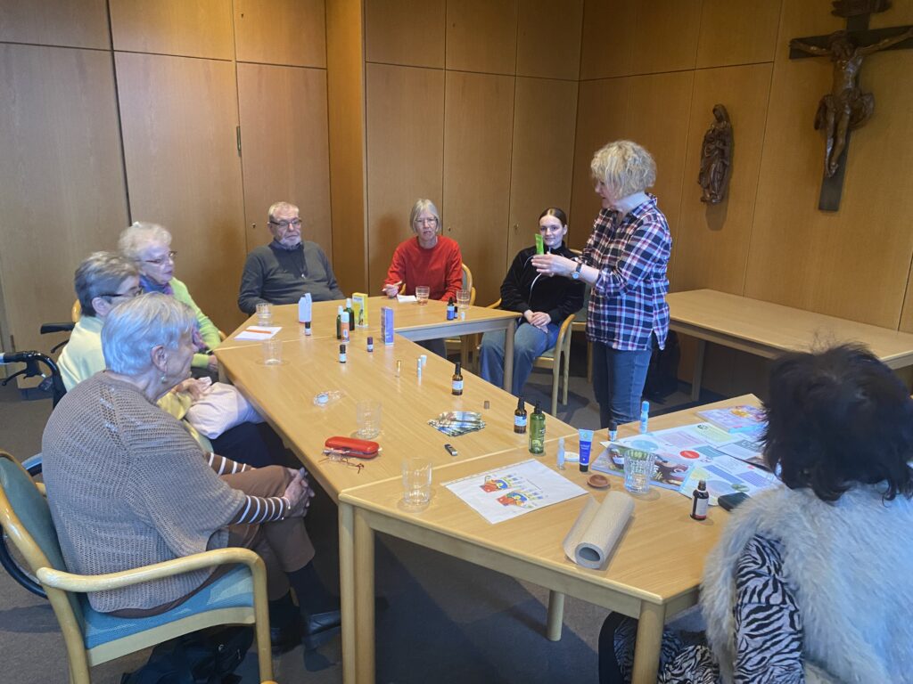 Sechs Personen hören einer Referentin zu, die über Aromatherapie informiert