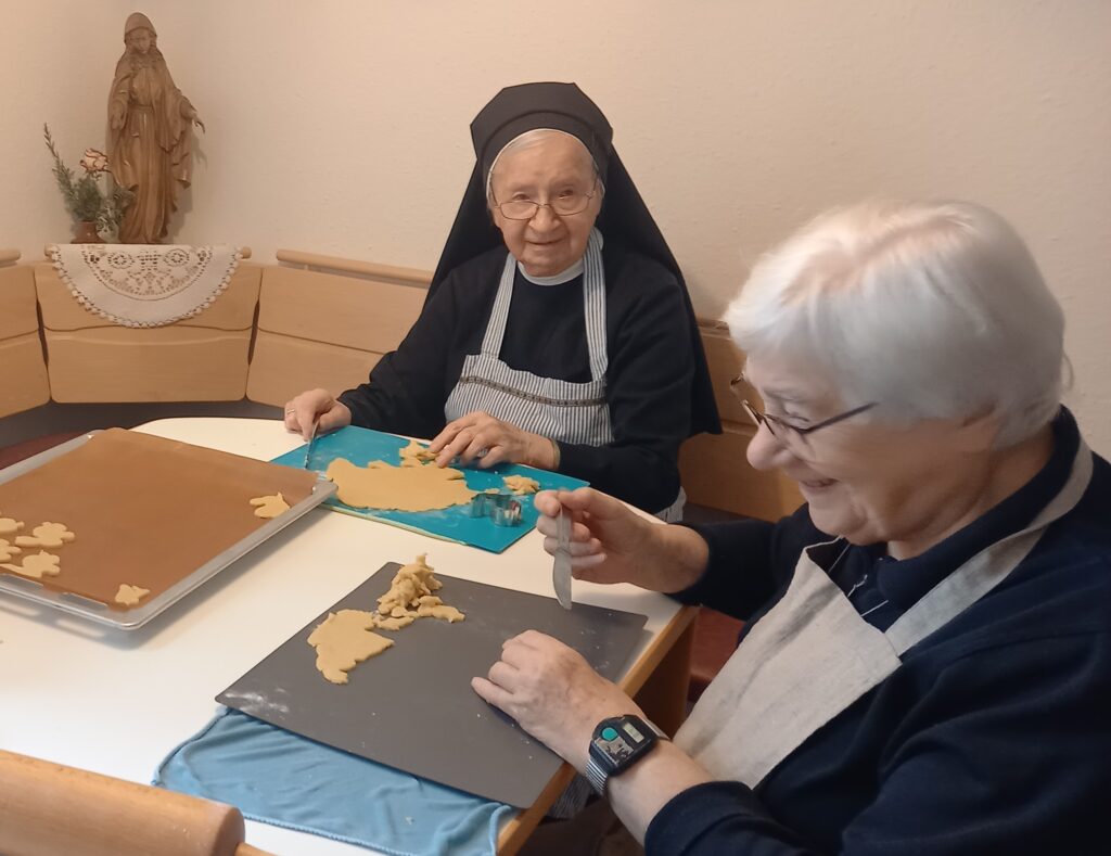 Zwei Schwestern stechen aus Teig Osterhasen aus und freuen sich dabei.